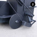 Close-up of a black kettle with a wheel on a light gray background
