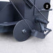 Close-up of a black kettle with a wheel on a light gray background