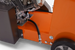 Close-up of an orange piece of machinery with a black tube and metallic components.