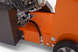 Close-up of an orange piece of machinery with a black tube and metallic components.