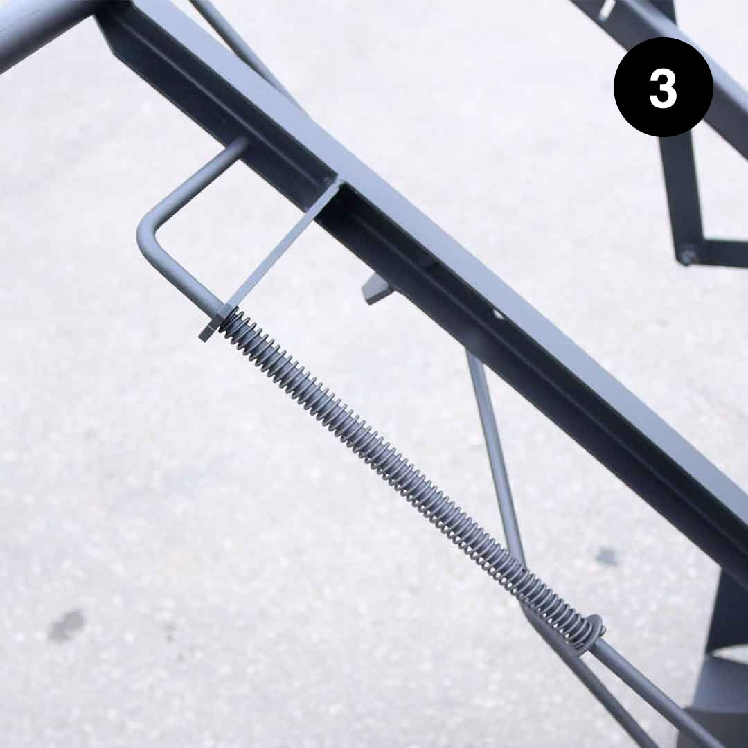 Metal spring attached to a mechanical component on a light gray background